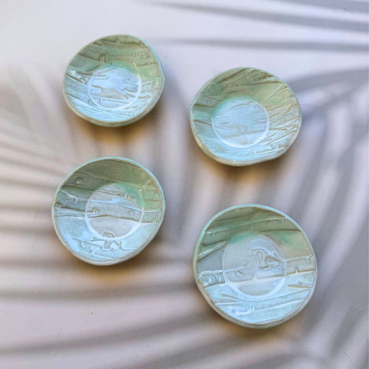 Four ceramic plates with textured surfaces on a textured white background. Sunshine Pot-Tree