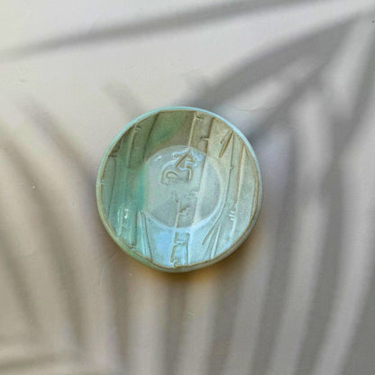 Ceramic ring dish with embossed design on a textured beige background. Sunshine Pot-Tree