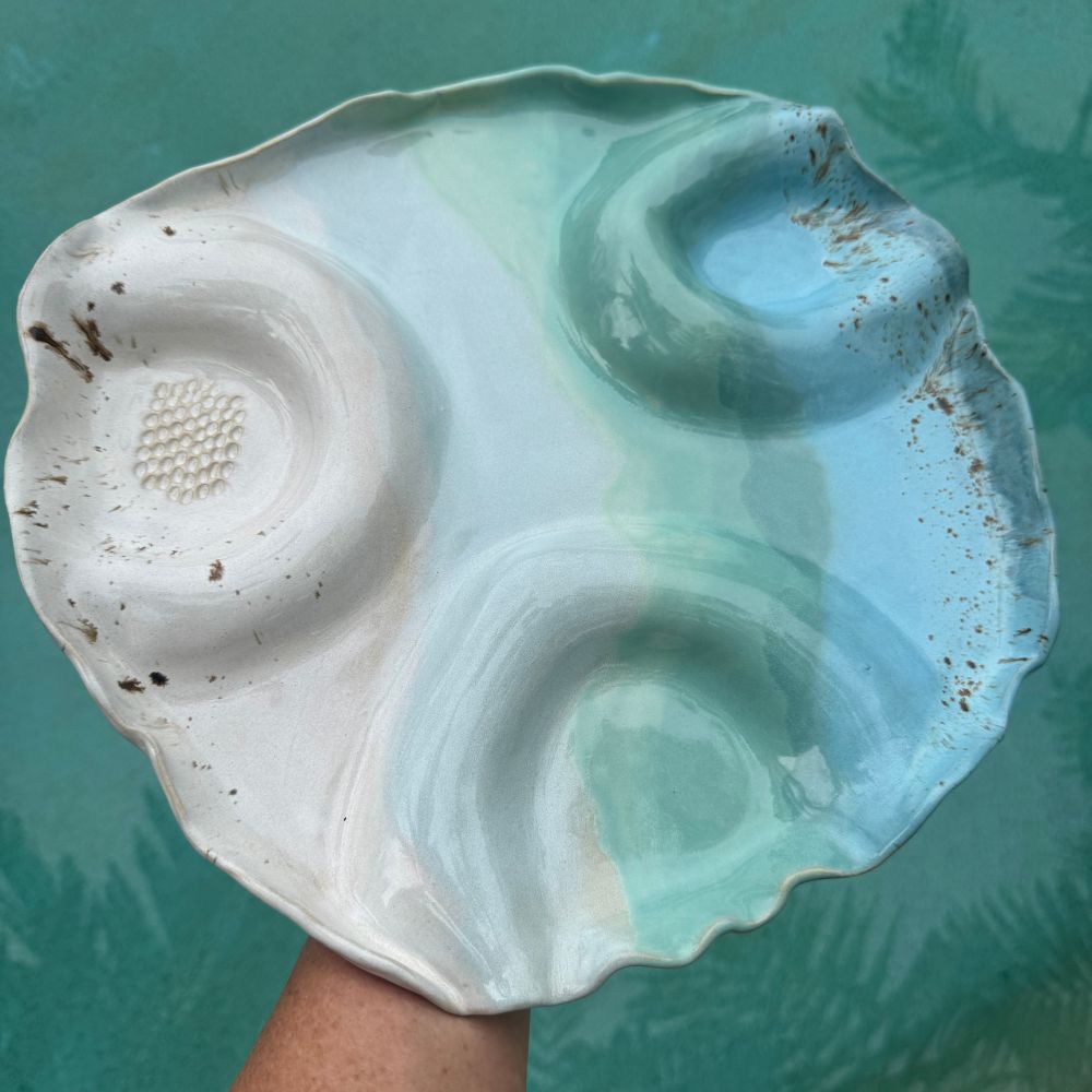 Ceramic grazing platter with a textured surface on a teal background