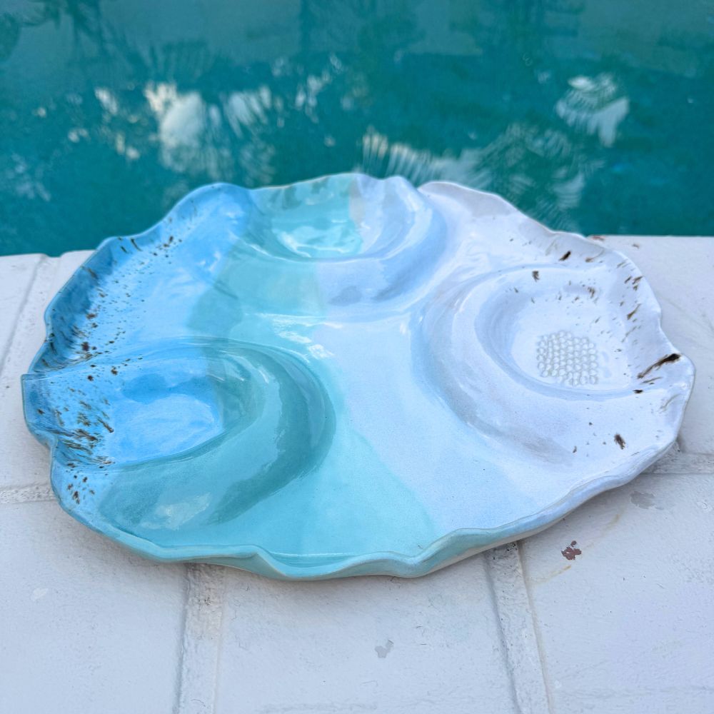Shell-shaped blue and white dish on a pool ledge