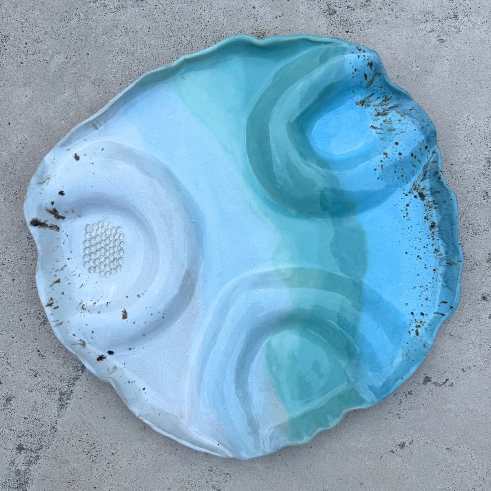 Ceramic grazing platter with a textured surface on a teal background