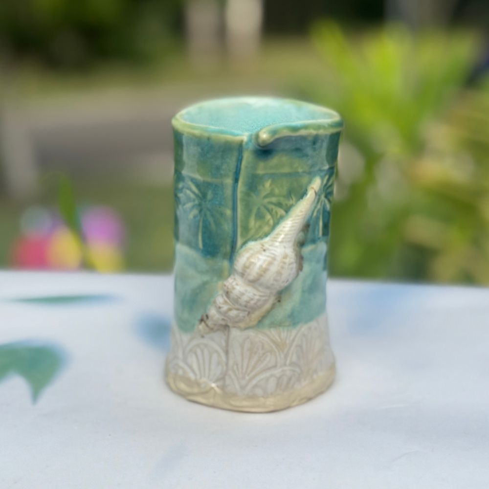 Ceramic vase with shell design on a blurred natural background