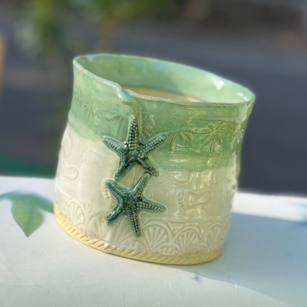 Decorative ceramic planter with starfish design on a blurred natural background