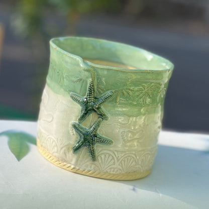 Decorative ceramic planter with starfish design on a blurred natural background