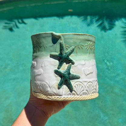 Ceramic planter with starfish design held against a teal background