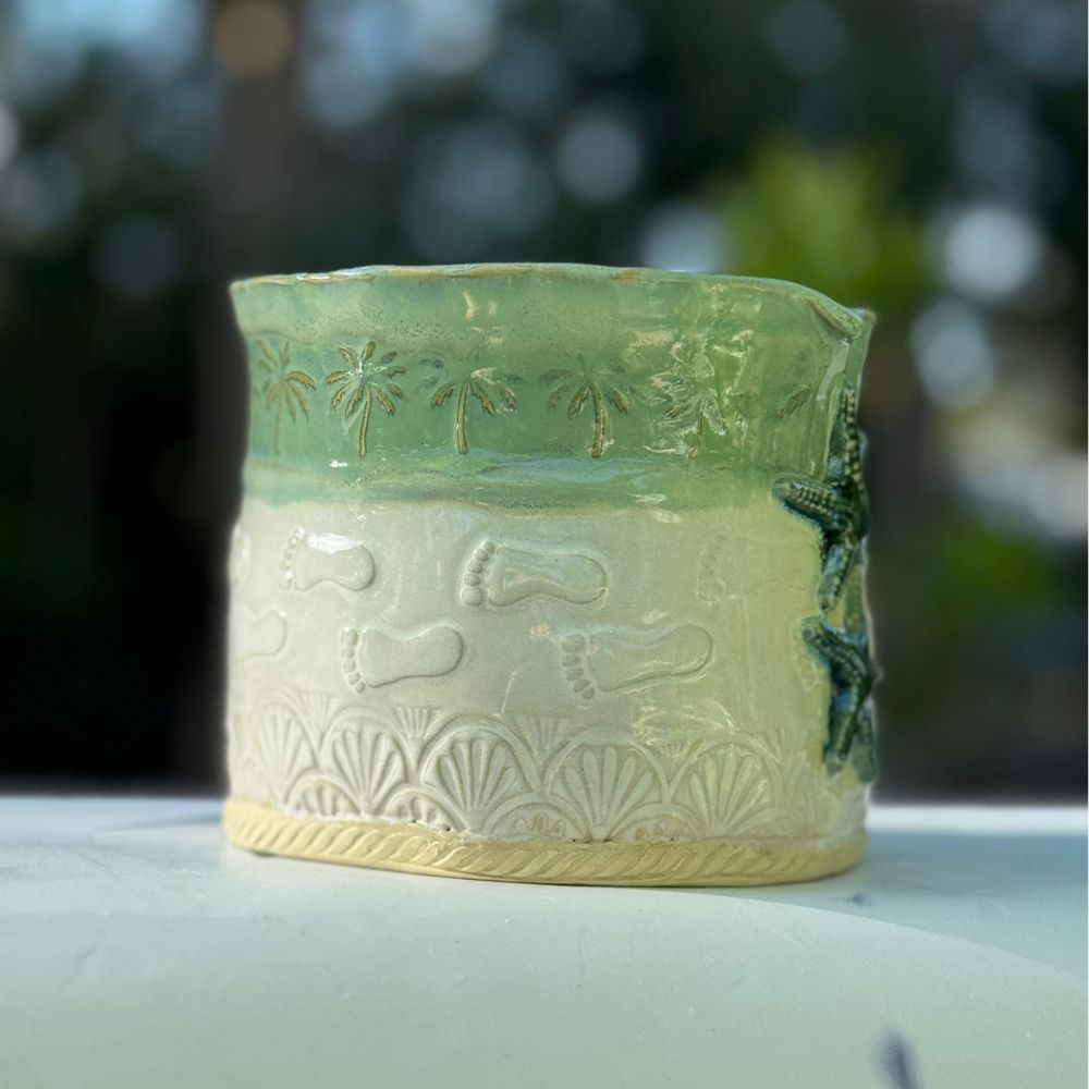 Ceramic planter with green and beige patterns on a blurred natural background