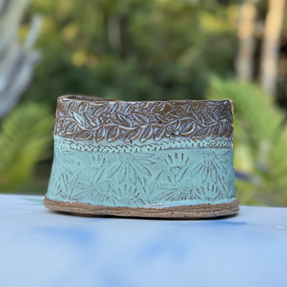 Handmade turquoise ceramic planter with floral texture