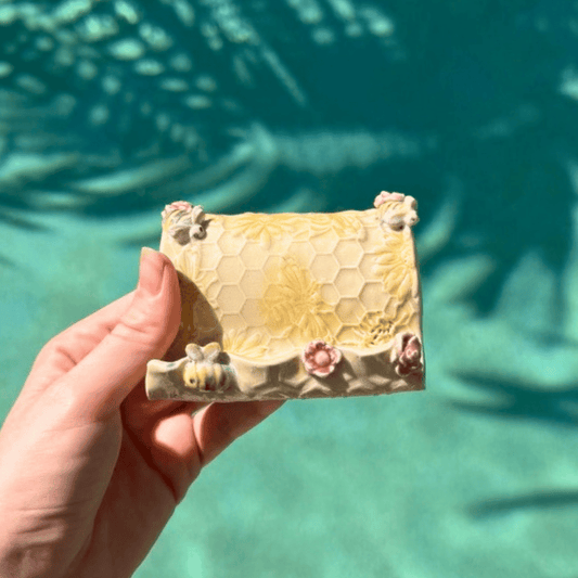 Hand holding a honeycomb-shaped business card holder with flowers against a blurred natural background