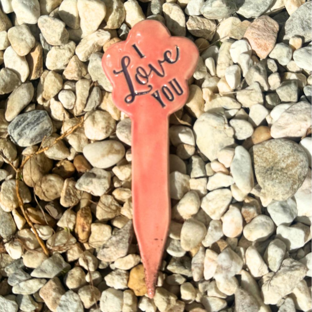 Pink heart-shaped 'I Love You' sign on pebbles