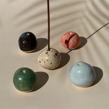Five ceramic beads in different colors on a beige surface