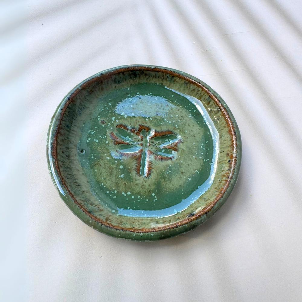 Green ceramic plate with a dragonfly design on a white background