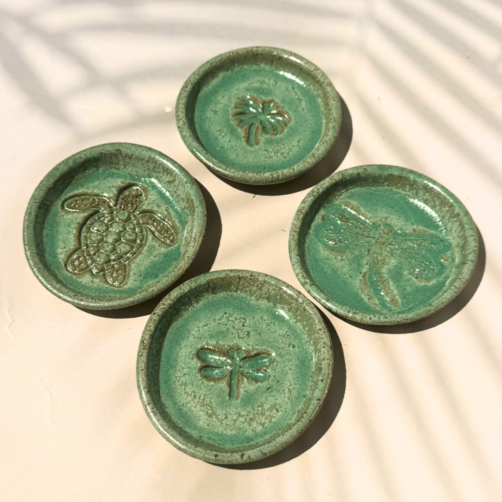 Four green ceramic trinkets with animal designs on a light background