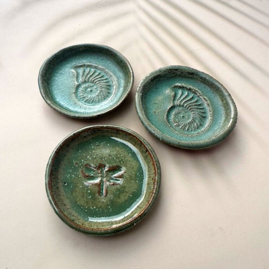 Three green ceramic dishes with embossed designs on a light background