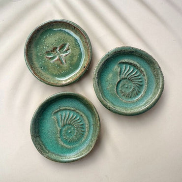 Three green ceramic coasters with decorative patterns on a light background