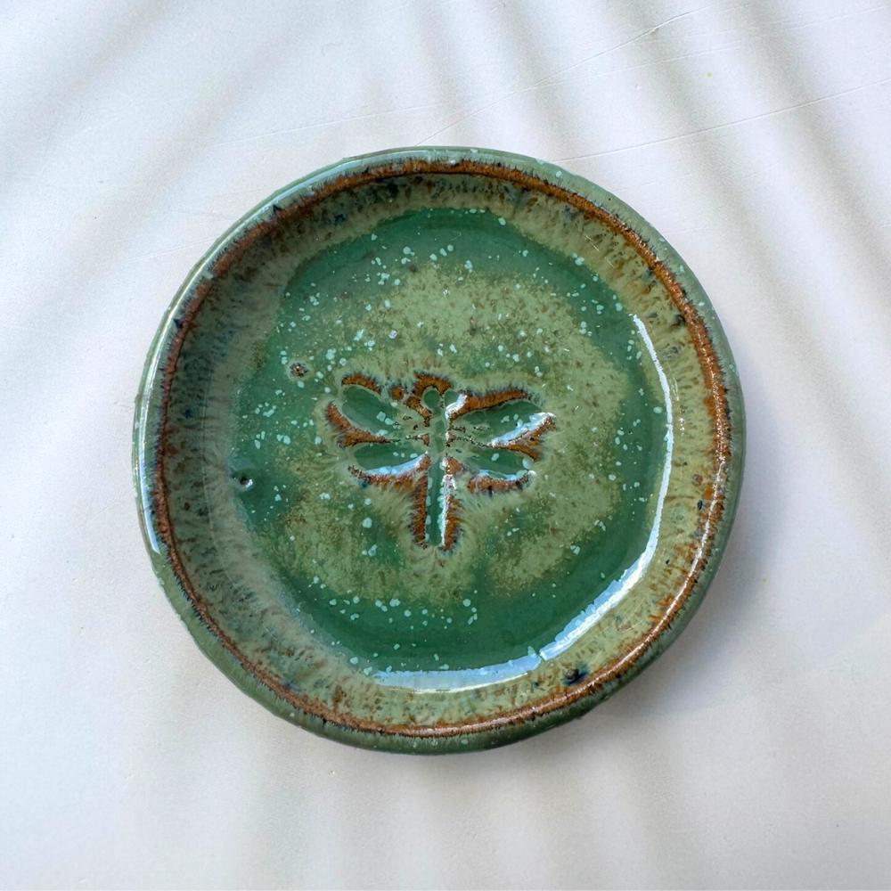 Green ceramic plate with a dragonfly design on a white background