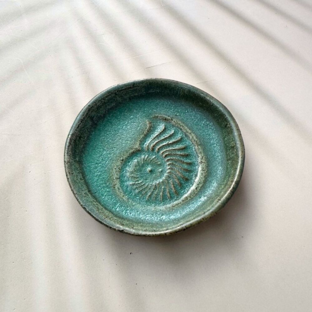 Green ceramic dish with decorative pattern on a light background