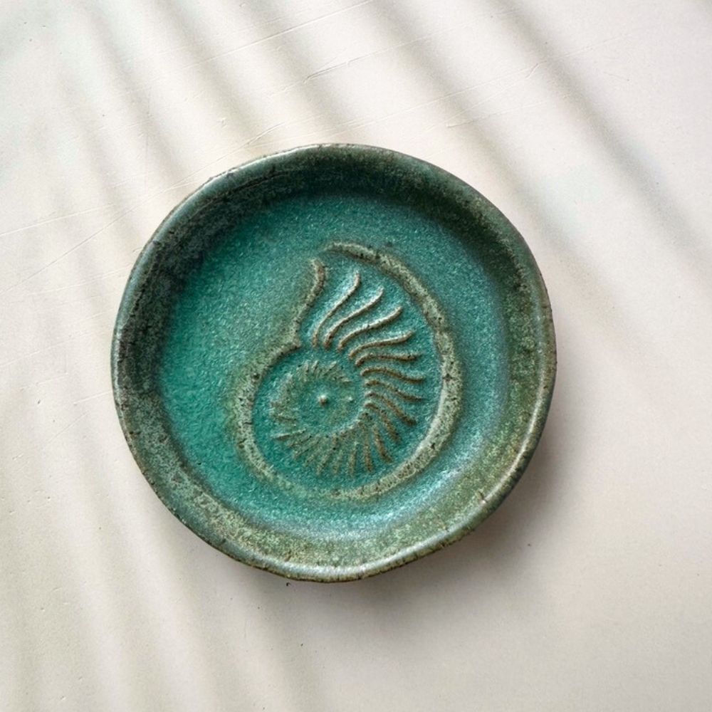 Green ceramic dish with a sun design on a light background