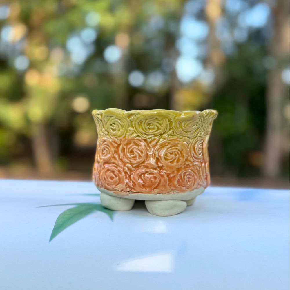 Decorative ceramic pot with a textured design on a blurred natural background