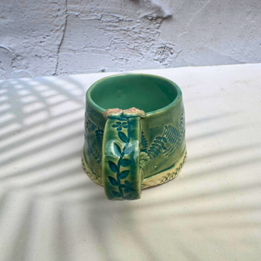 Handmade green botanical mug with leafy handle and sculpted flower