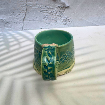 Handmade green botanical mug with leafy handle and sculpted flower