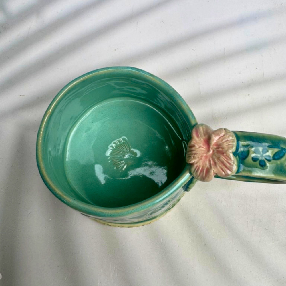 Inside of green ceramic mug featuring a surprise coneflower detail