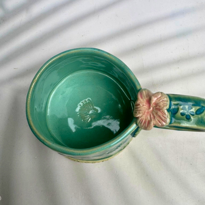 Inside of green ceramic mug featuring a surprise coneflower detail