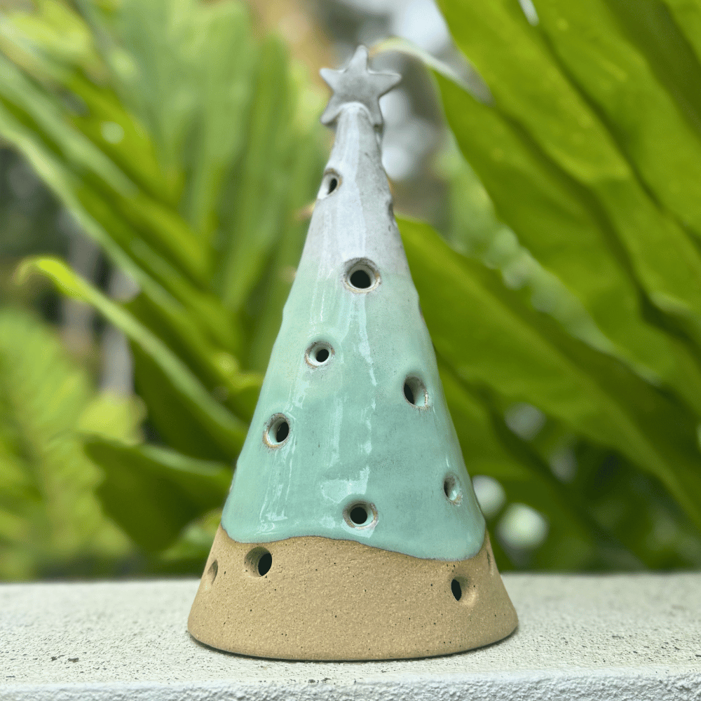 Ceramic incense burner shaped like a Christmas tree with a star on top, set against a green leafy background. Handmade in Australia.