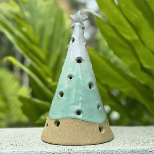 Ceramic incense burner shaped like a Christmas tree with a star on top, set against a green leafy background. Handmade in Australia.