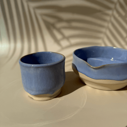 Two blue ceramic matcha bowls on a beige surface with a textured background
