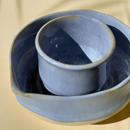 Blue ceramic dish with a smaller bowl inside on a beige background
