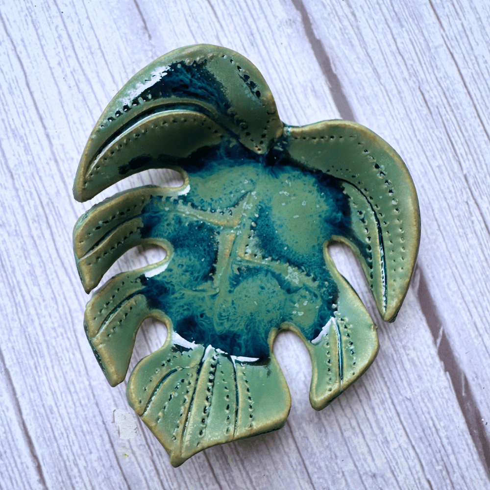 Green ceramic leaf-shaped dish on a light wooden surface