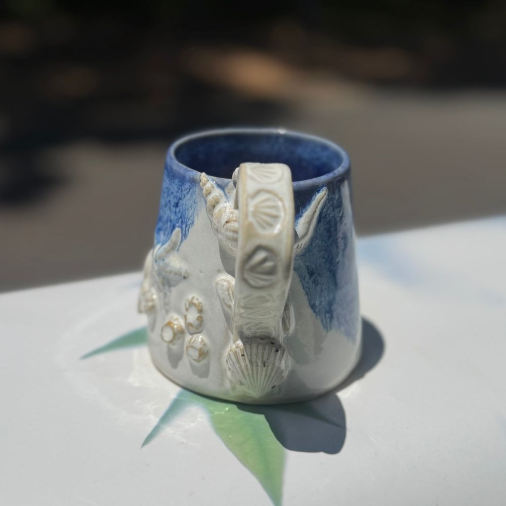 Ceramic mug with shell designs on a white surface