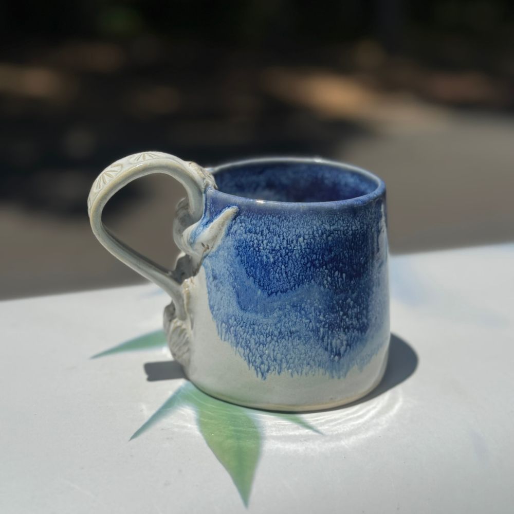 Ceramic mug with blue and white design on a reflective surface