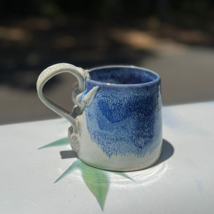 Ceramic mug with blue and white design on a reflective surface