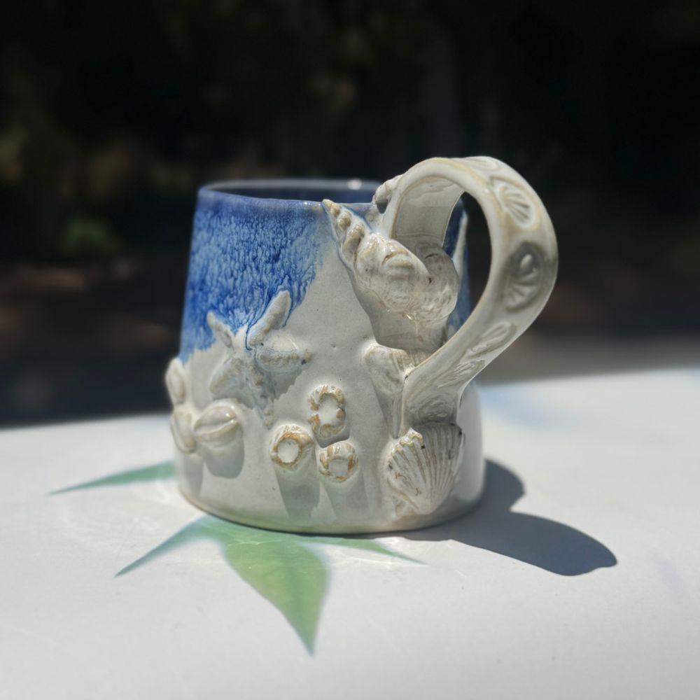 Ceramic mug with decorative handle on a white surface
