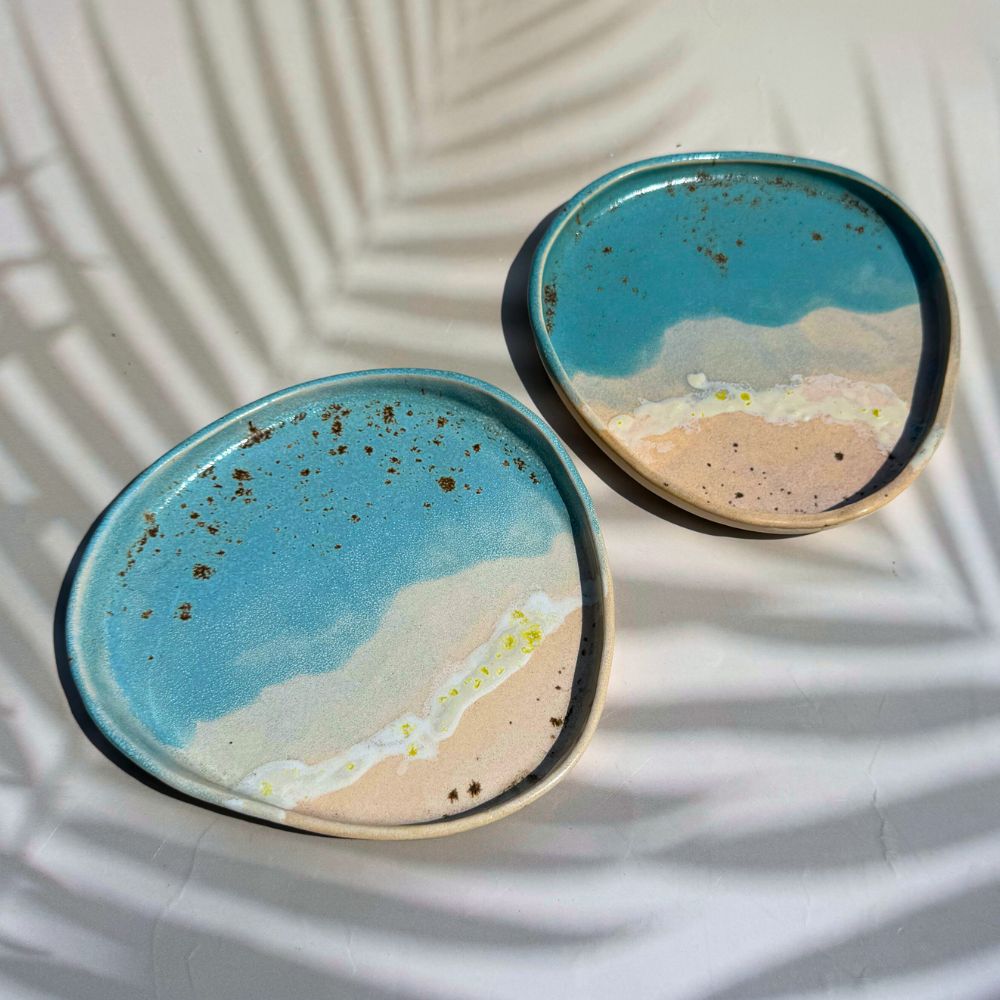 Two ceramic plates with a beachscape design on a white surface.