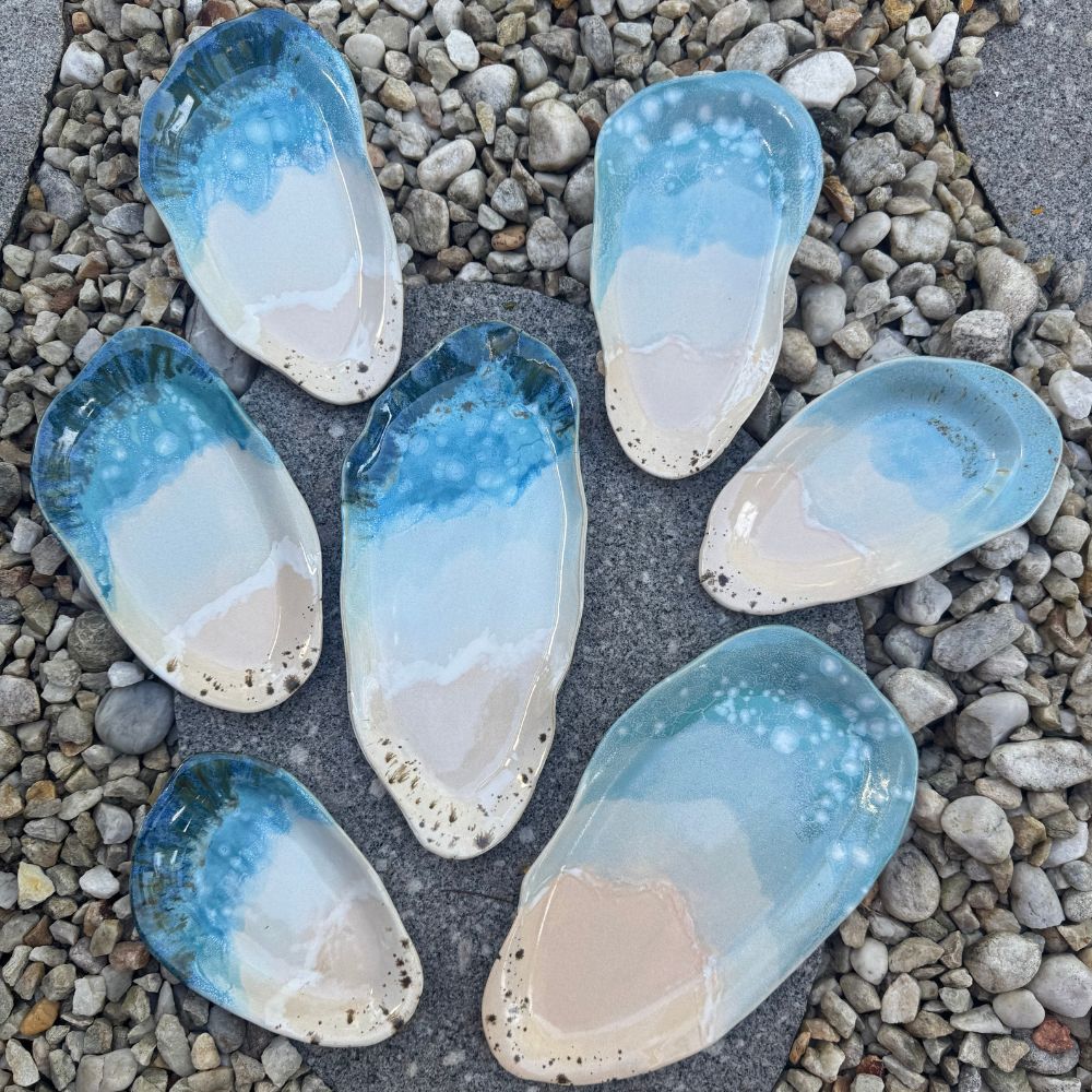 ceramic platters pieces resembling seashells on a pebble surface