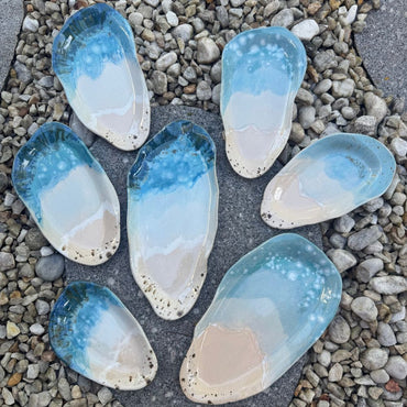 ceramic platters pieces resembling seashells on a pebble surface