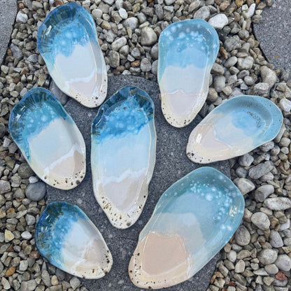 ceramic platters pieces resembling seashells on a pebble surface
