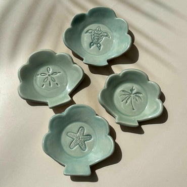 ceramic dishes in the shape of a shell with tropical imprints
