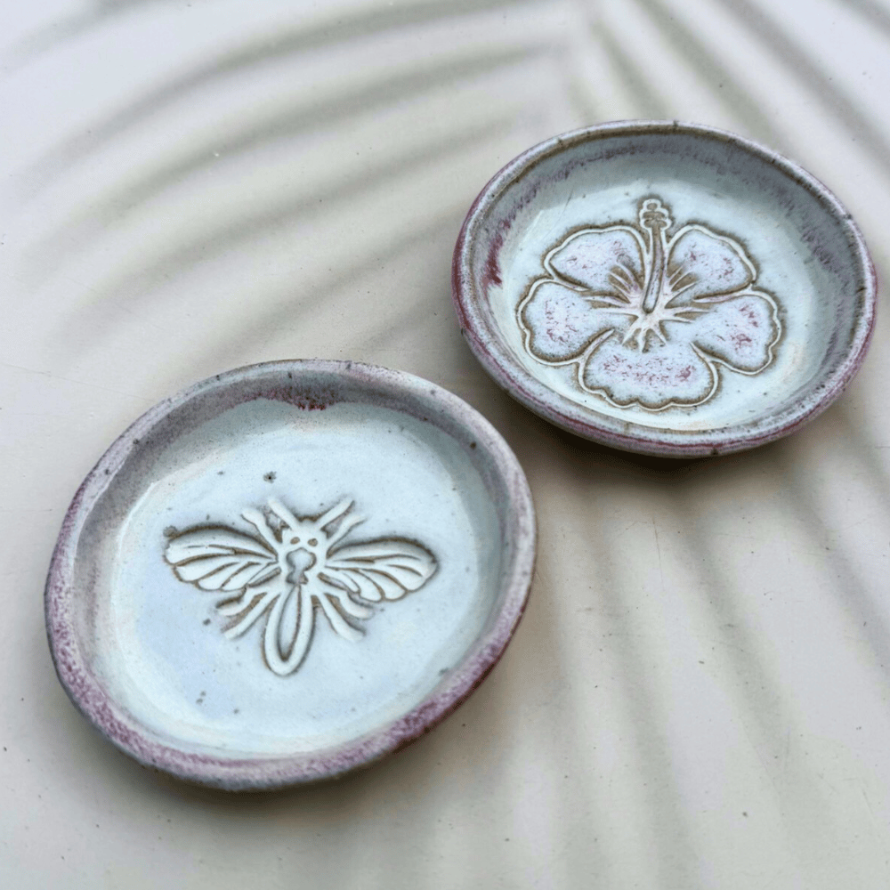Two ceramic dishes with floral designs on a textured surface