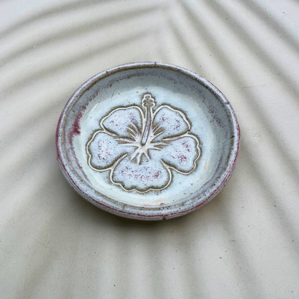 Ceramic dish with floral design on a textured beige surface