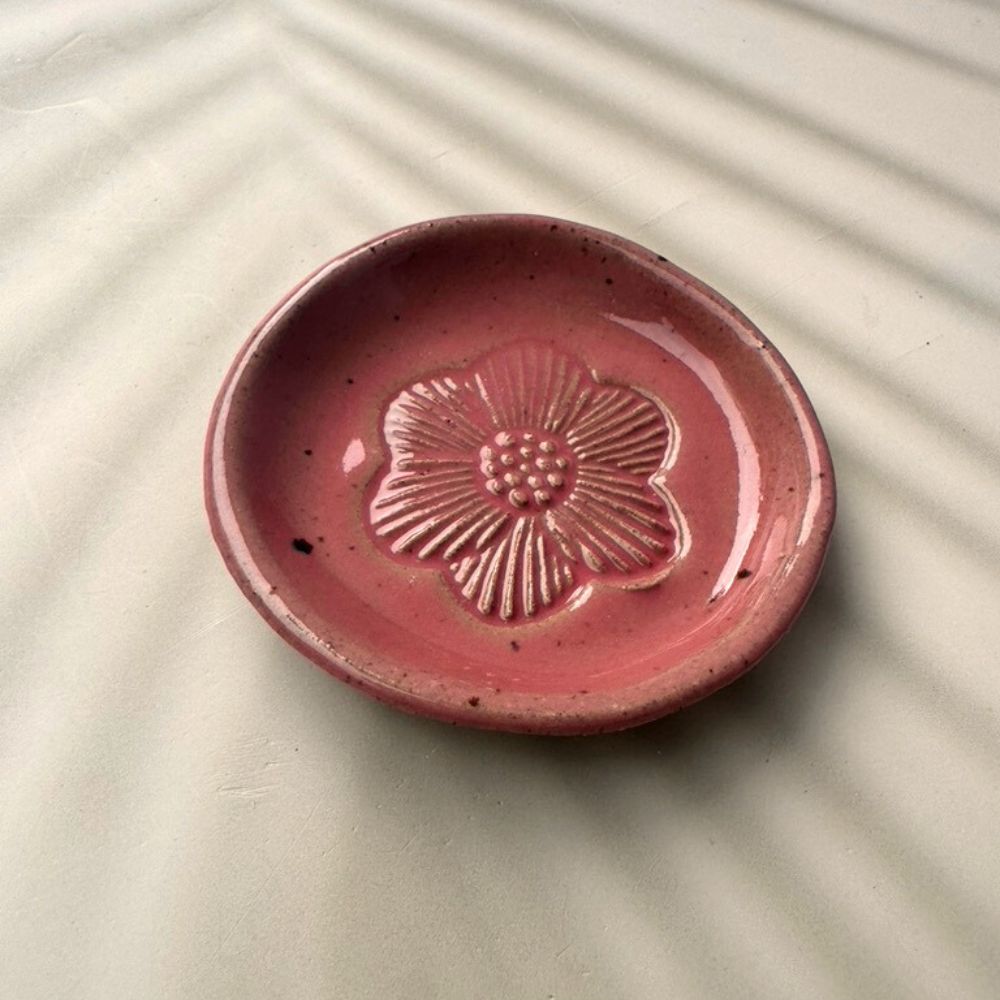 Pink ceramic dish with floral design on a beige surface