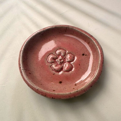 Pink ceramic dish with floral design on a beige surface