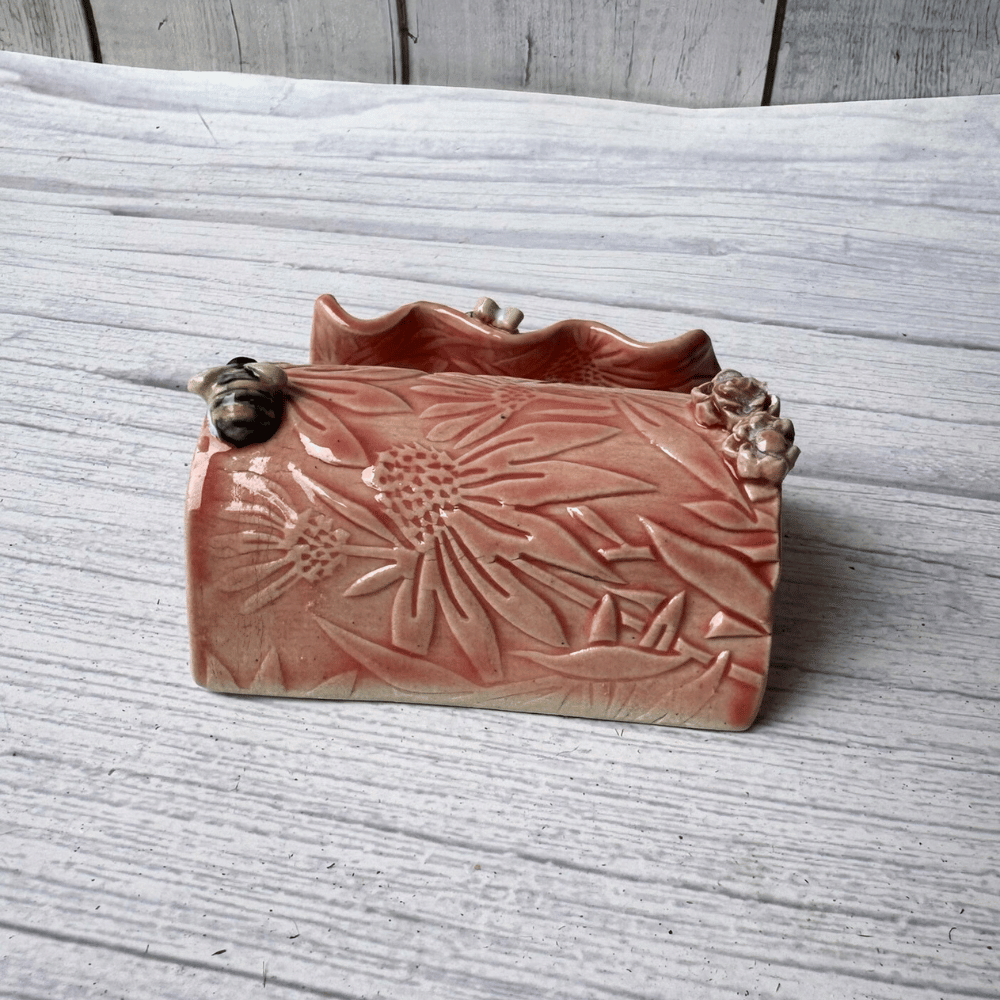 Ceramic business card holder with floral patterns on a wooden surface