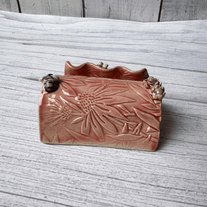 Ceramic business card holder with floral patterns on a wooden surface