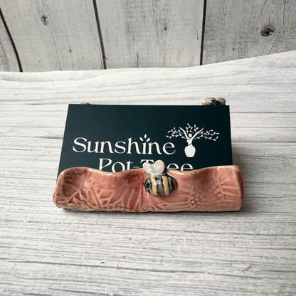 Ceramic business card holder with floral and bee patterns on a wooden surface