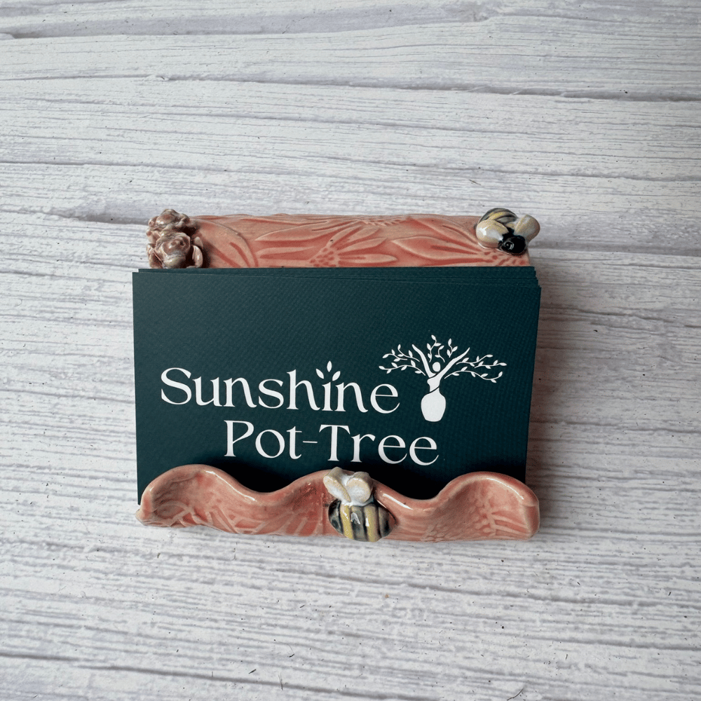 Ceramic business card holder with floral and bee patterns on a wooden surface