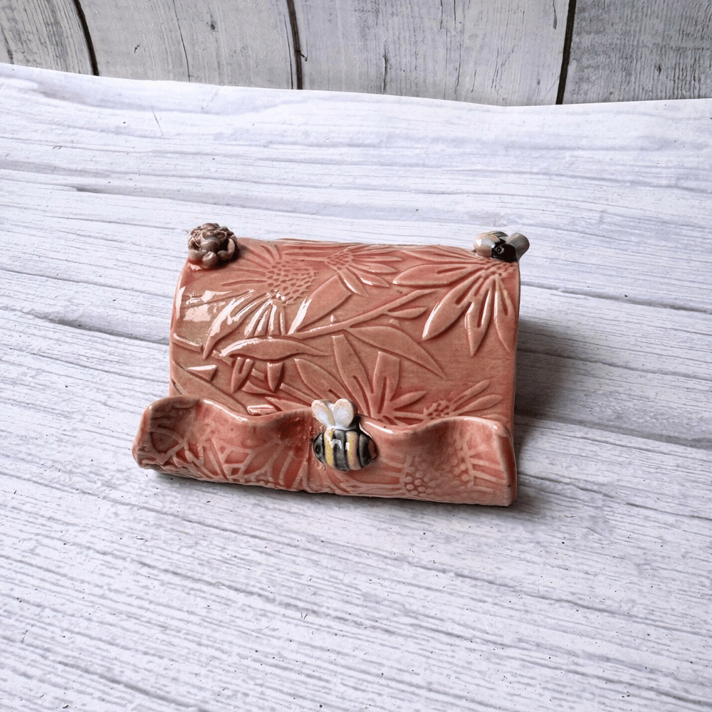 Ceramic business card holder with floral and bee patterns on a wooden surface