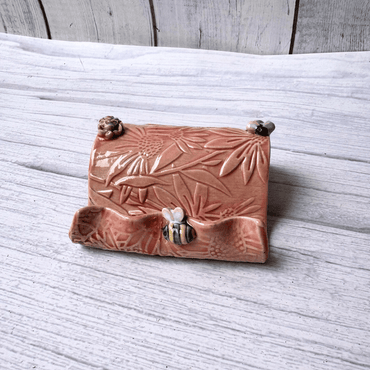 Ceramic business card holder with floral and bee patterns on a wooden surface